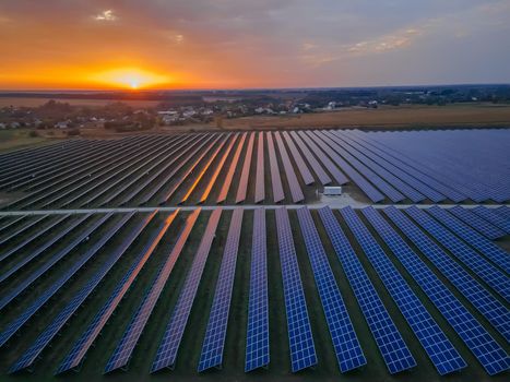 Aerial drone view of large solar panels at a solar farm at bright summer sunset. Solar cell power plants, colorful photo