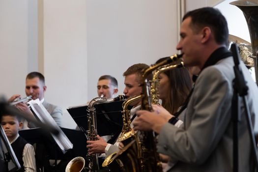 KOROSTEN - NOV, 10, 2019: Young people play in the orchestra on different musical instruments in gray suits.
