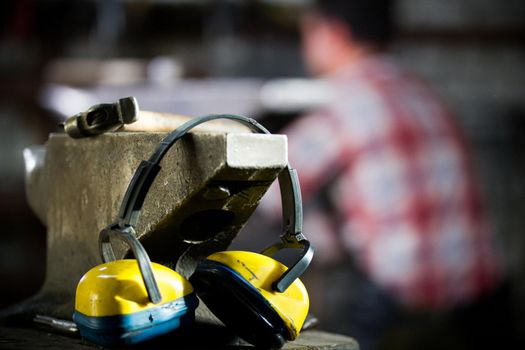 Workspace of blacksmith. the hammer, headphones and gloves lie on the anvil. Close up shot