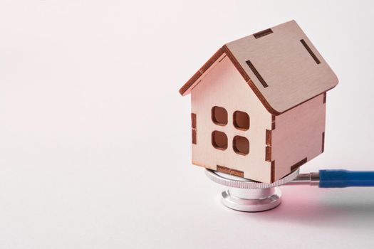 Medical stethoscope and toy house on a pink background with copy space