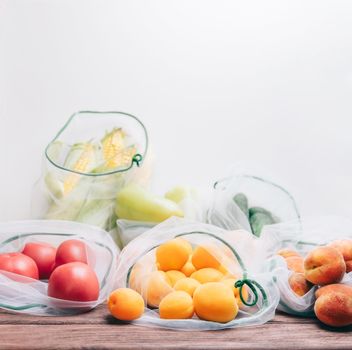 Different fresh fruits and vegetables in reusable eco mesh bags. Zero waste and free plastic concept.