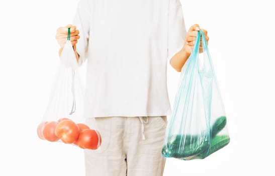 Unrecognizable woman holding a reusable eco mesh bag and a plastic package with vegetables. Zero waste concept.