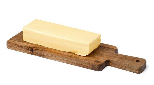 Butter on wooden board isolated on white background, close up