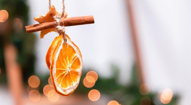 Hanging Christmas decoration of dried oranges, tangerine and cinnamon stars with copy space for text. holiday concept. blurred background.