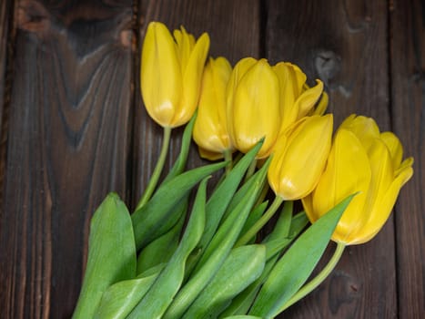 Yellow tulips lie on a wooden rustic table. Spring holidays concept background and mother's day.