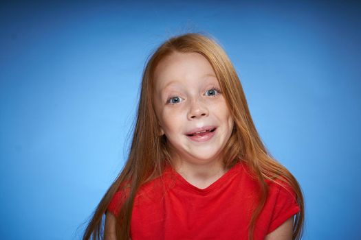 cute red-haired girl in red t-shirt emotions blue background. High quality photo