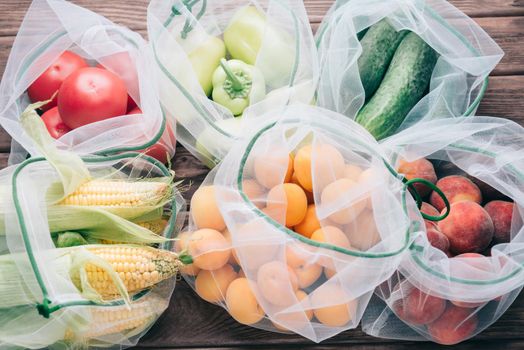 Fruits and vegetables in reusable eco mesh bags on a wooden background. Zero waste and free plastic concept.