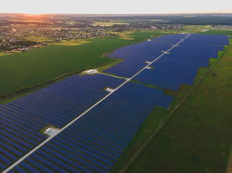 Aerial drone view of large solar panels at a solar farm at bright summer sunset. Solar cell power plants, colorful photo