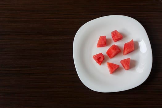 Slices of watermelon on a white plate on a dark background