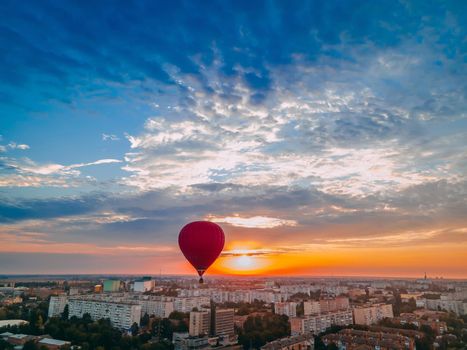 Red hot air balloon flying over small european city at summer sunrise, Kiev region, Ukraine