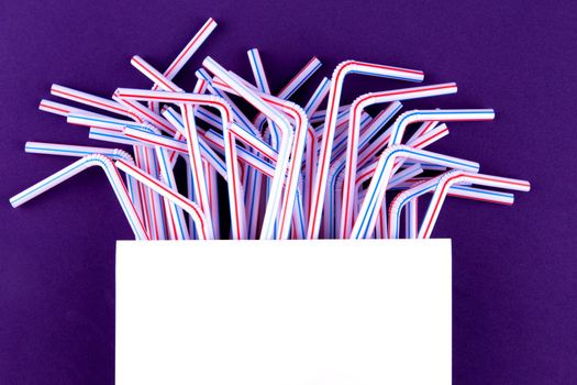Coctail plastic tubes on blue purple background. Environmental concept. Ban single use plastic campaign. Copy space for text