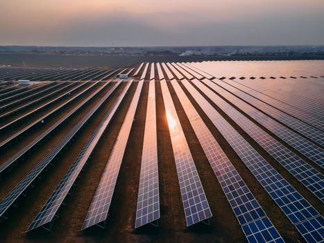 Aerial drone view of large solar panels at a solar farm at bright spring sunset. Solar cell power plants, colorful HDR photo