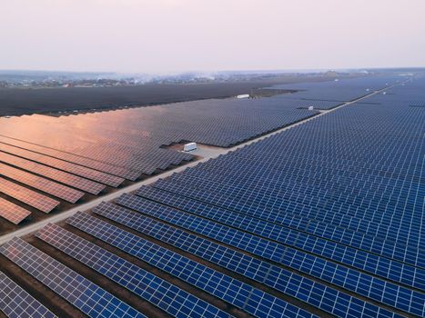 Aerial drone view of large solar panels at a solar farm at bright spring windy sunset. Solar cell power plants, colorful photo