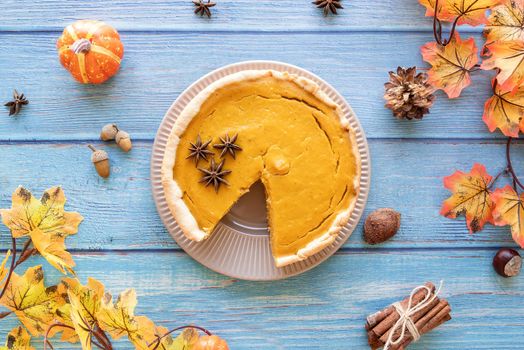 Autumn concept. Homemade pumpkin pie with autumn leaves on rustic background, top view flat lay