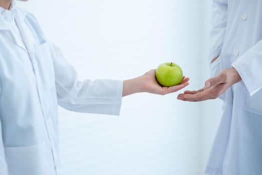 green apple that young scientist student girl give to her teacher for symbol of respect before study in laboratory or classroom.