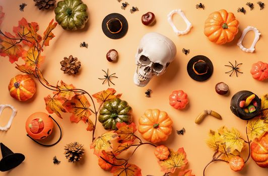 Halloween concept. Halloween holiday decorations with pumpkins and candies top view on orange background