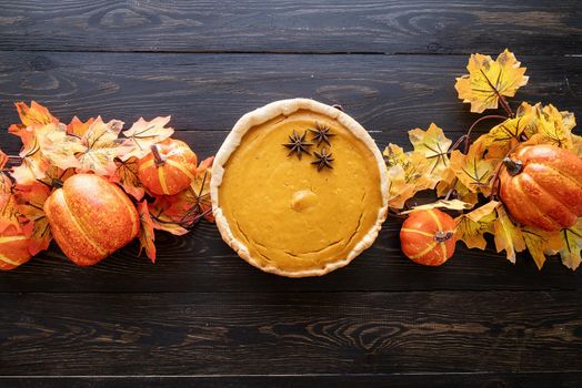 Autumn concept. Homemade pumpkin pie with autumn leaves on rustic background, top view flat lay