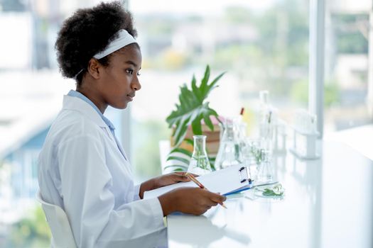 African American young hold clipboard or document file and look to right side during do experiment in laboratory or classroom.