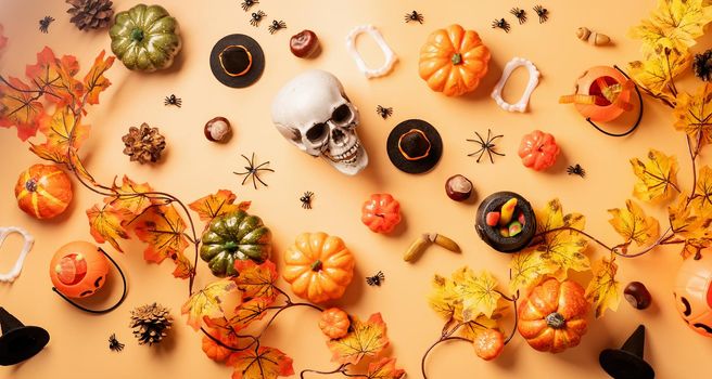 Halloween concept. Halloween holiday decorations with pumpkins and candies top view on orange background