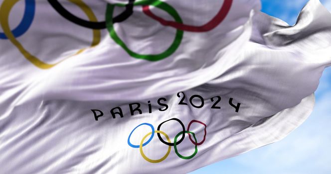 Tokyo, Japan, July 2021: Paris 2024 flag waving in the wind with the Olympic flag blurred in the foreground. Paris 2024 summer olympics games are scheduled from 26 July to 11 August 2024 in Paris
