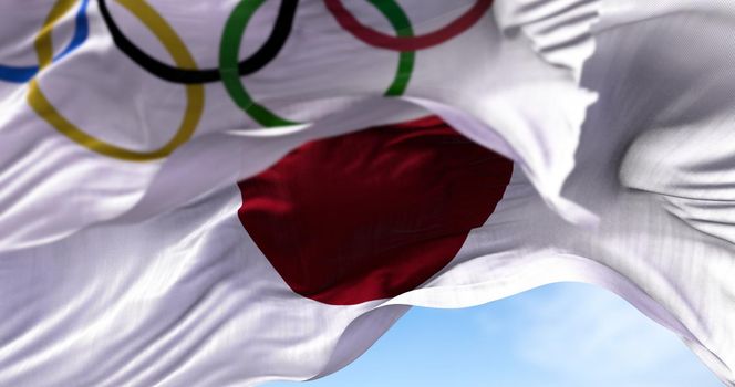 Tokyo, Japan, July 2021: The national flag of Japan waving with the Olympic flag blurred in the foreground. Tokyo 2020 olympics games were postponed to 2021 due to the covid-19 pandemic