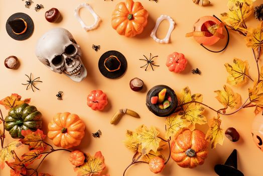 Halloween concept. Halloween holiday decorations with pumpkins and candies top view on orange background