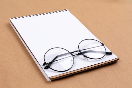 Stationary concept, Flat Lay top view Photo of glasses and notepad on a beige abstract background with copy space, minimal style