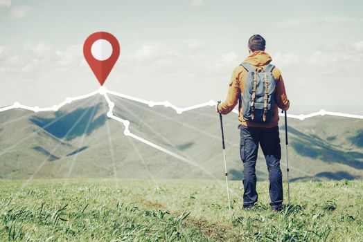 Hiker backpacker young man with trekking poles standing in front of route with location GPS pin on peak of mountain ridge in summer outdoor.