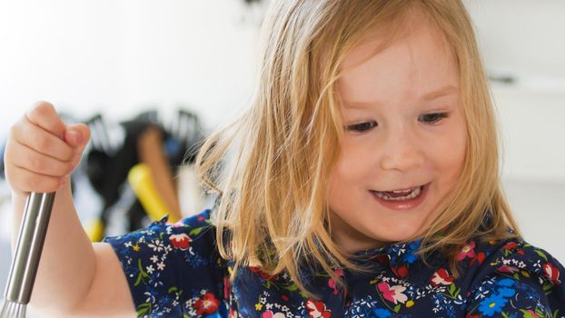 Little pretty girl on the kitchen makes cookies, close up