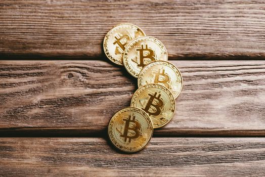 Symbol of crypto currency and virtual money - bitcoins on a wooden table, close-up.