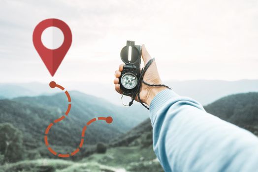 Male explorer searching direction with magnetic compass in mountains and route with connected location pins, point of view. Navigation concept.