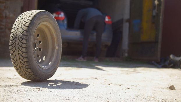 Car wheels rolling on the ground in front of car garage, close up