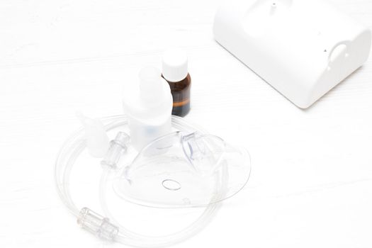 nebulizer and accessories for it on a light background, copy space, inhaler and mask, medicine for inhalation, compressor type