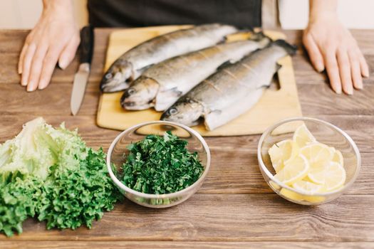 Food ingredients for seafood fish dish on table in front of chef woman in the kitchen.