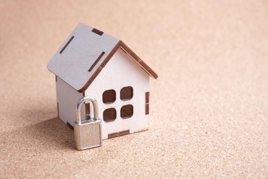wooden toy house and a small padlock on a cork board, property protection concept