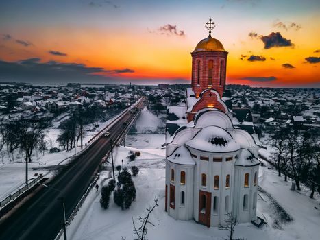 Aerial view of the church in snow-covered small european city at bright winter sunset Gorgeous sunset and clouds.. Drone. Winter. Ukraine, 2021