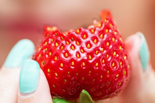 Woman holding fresh ripe strawberry in fingers. Selective focus