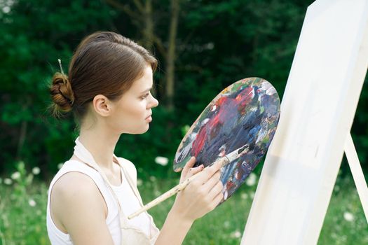 woman artist paints palette easel nature drawing. High quality photo