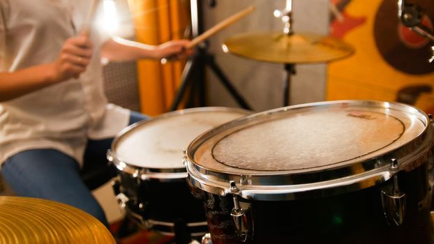 Repetition. Ginger girl plays on drums in the studio. Focus on drums. Mid shot