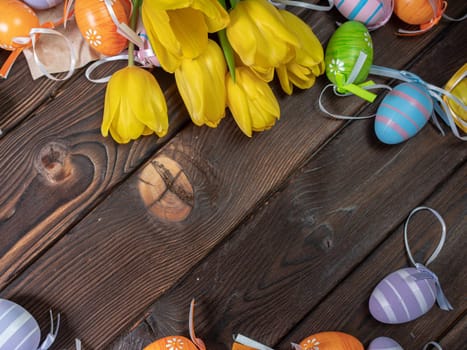 Multicolored painted Easter eggs with tulips on a wooden board. Easter holiday concept.