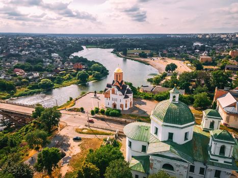 Aerial view of two old churches near river and bridge in small european city at summer day, Kyiv region, Ukraine