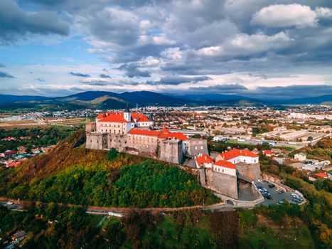 Aerial view of medieval castle on mountain in small european city in autumn season. Palanok castle, Mukachevo, Ukraine