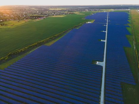 Aerial drone view of large solar panels at a solar farm at bright summer sunset. Solar cell power plants, colorful photo