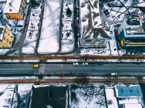 Aerial top down view of road in small european city with snow covered roofs at winter cloudy day