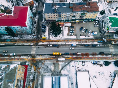 Aerial top down view of road in small european city with snow covered roofs at winter cloudy day