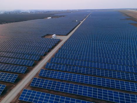 Aerial drone view of large solar panels at a solar farm at bright spring windy sunset. Solar cell power plants, colorful photo