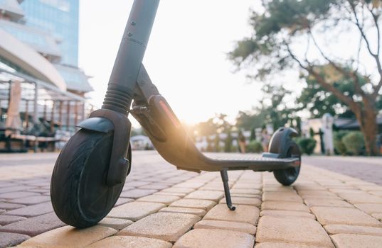 Electric scooter in city summer park at sunset.