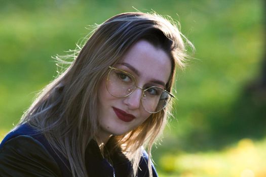 Beautiful girl in glasses with red lipstick looking in the camera. Natural contour lighting. Portrait