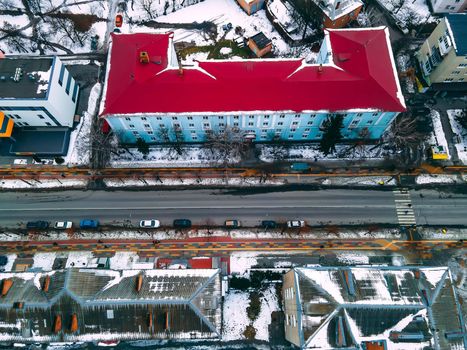 Aerial top down view of road in small european city with snow covered roofs at winter cloudy day