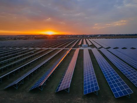 Aerial drone view of large solar panels at a solar farm at bright summer sunset. Solar cell power plants, colorful photo